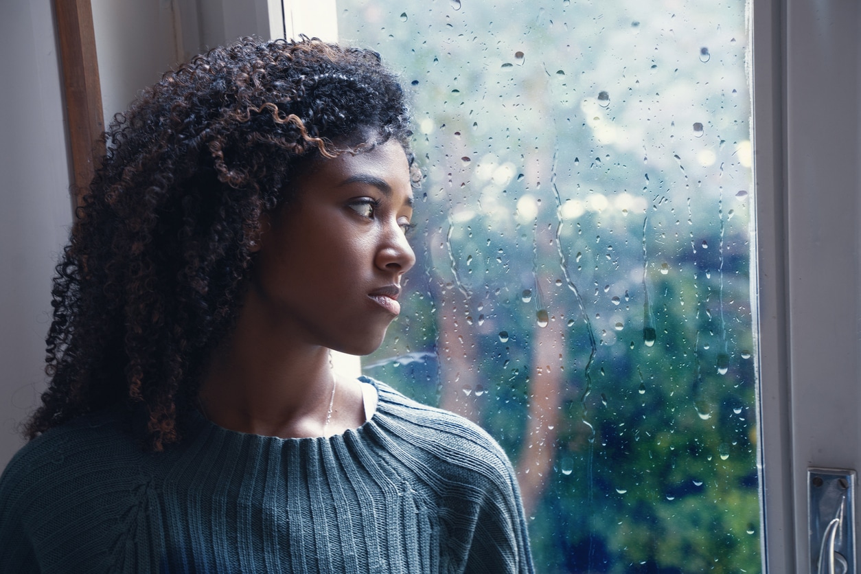jeune femme qui regarde la pluie dehors